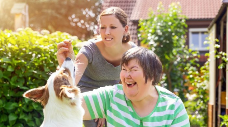 Lady with learning disabilities and her carer playing with a dog