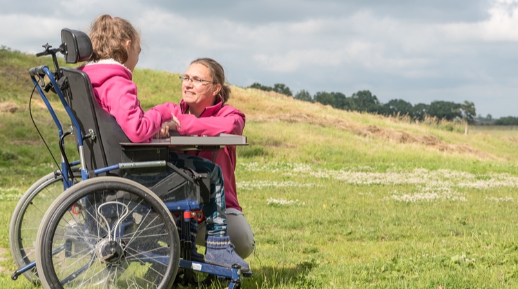 Woman kneeling, talking to a child in a wheelchair