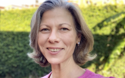 'Head and shoulders' portrait of MA Education student Marielle. She is wearing a pink sweater and smiling at the camera.