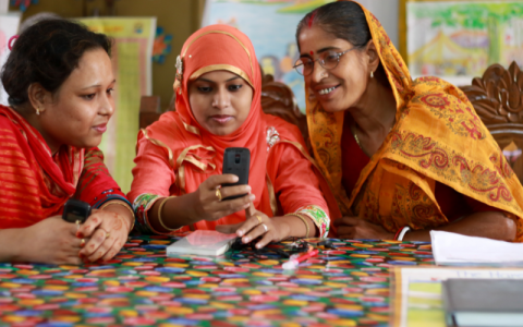 3 women studying with a mobile phone.