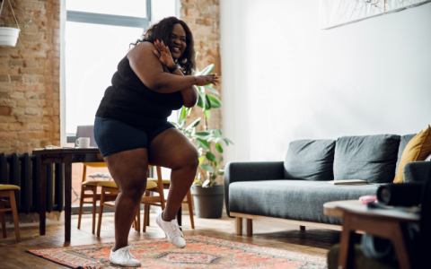 Joyful woman in sport clothes dancing at home