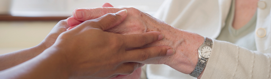 Carer holding elderly woman's hands