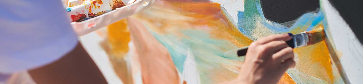 A close up of a painter's hand brushing colour on a wall