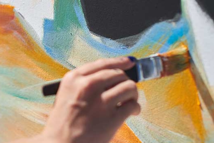 a close up of a hand painting a wall with a brush