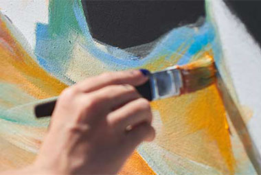 a close up of a hand painting a wall