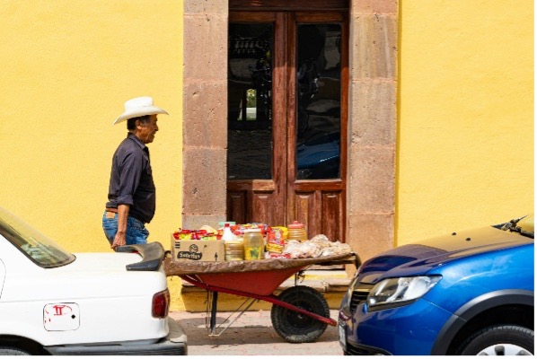 a man with a pushcart walking down a street