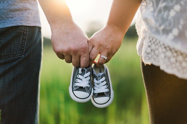Parents holding hands, holding a pair of baby shoes