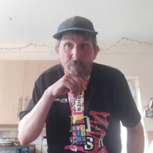 Craig Hart holding two Refreshers and wearing a baseball hat