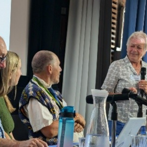 A photo of Jan Walmsley holding a microphone and smiling at Craig Hart, Liz Tilley and Ian Davies