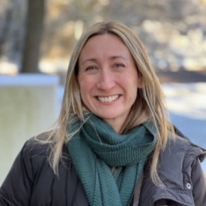 Portrait of Liz Tilley smiling at the camera and wearing a green scarf