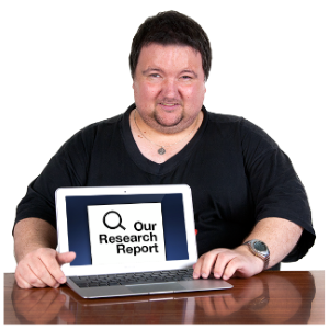 A man sat at a table with a laptop saying "our research report"