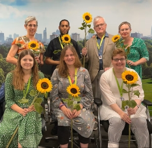 Group of people stood together holding large sunflowers