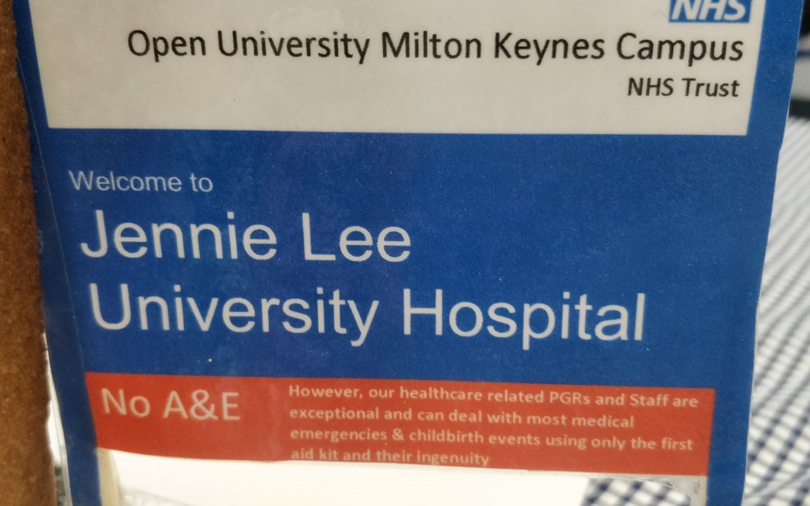 Close up detail on the hospital sign incorporated into Anna Madeley's bake. The sign is a replica of an NHS Hospital sign and reads, "Open University Milton Keynes Campus, NHS Trust, Welcome to Jennie Lee University Hospital, No A&E."