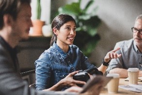 Young woman sat at a table and explaining to a group