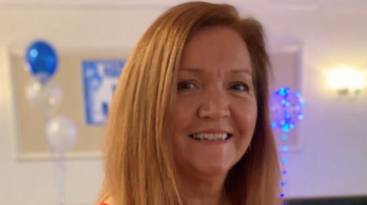 Portrait photograph of OU graduate Jo. She's facing the camera and smiling. In the background you can just see blue balloons