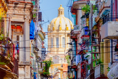 Colorful street in Old Havana with the Presidential Palace on the background