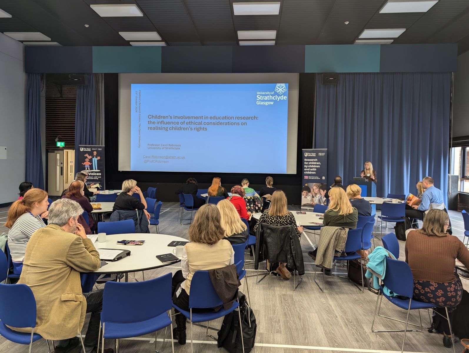 Image of an audience sat in a conference listening to a presentation from Professor Carol Robinson