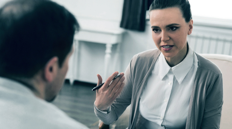 A female social worker uses her hand to explain as she talks to a male service user. . 