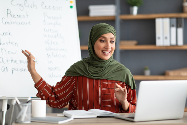Woman in a Hijab teaches English to students on a computer