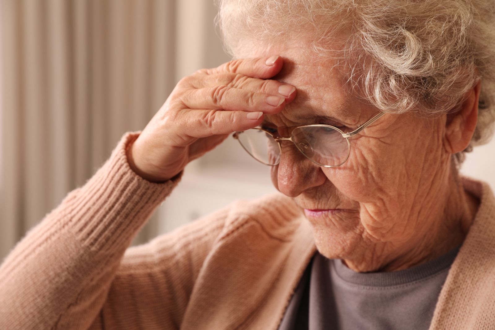 Senior woman with headache at home, closeup. Symptom of age-related memory impairmen
