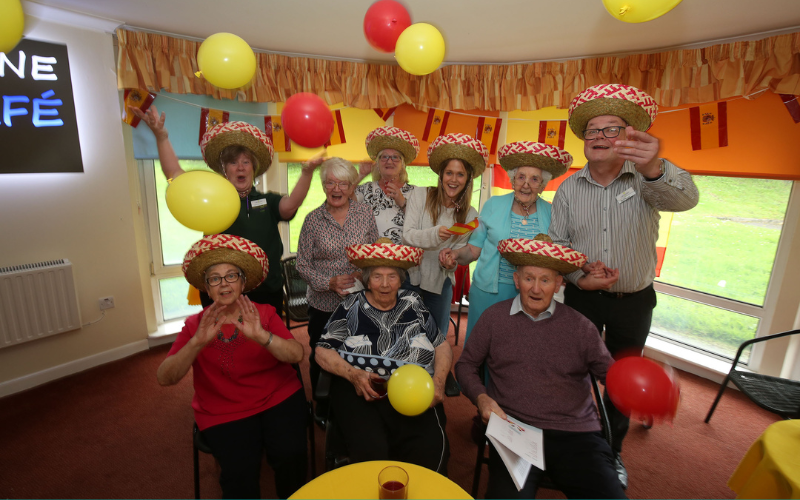 This is a group picture from a Lingo Flamingo where everyone’s wearing a hat and holding yellow and red balloons.