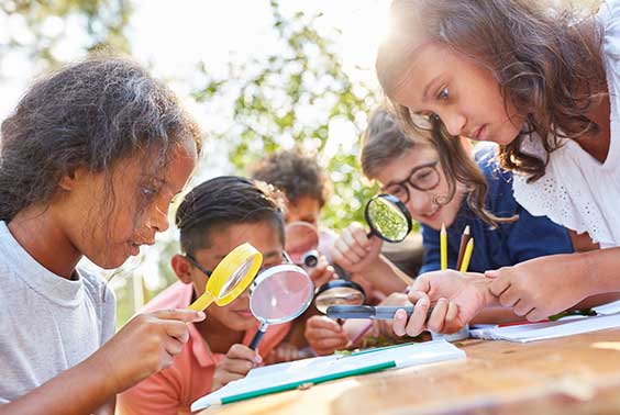 Children using magnifying glasses together.