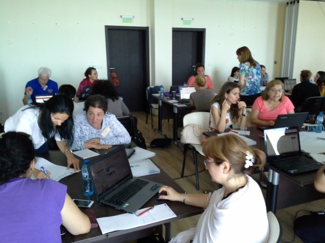 a group of workshop attendeed working in groups using laptops and notebooks