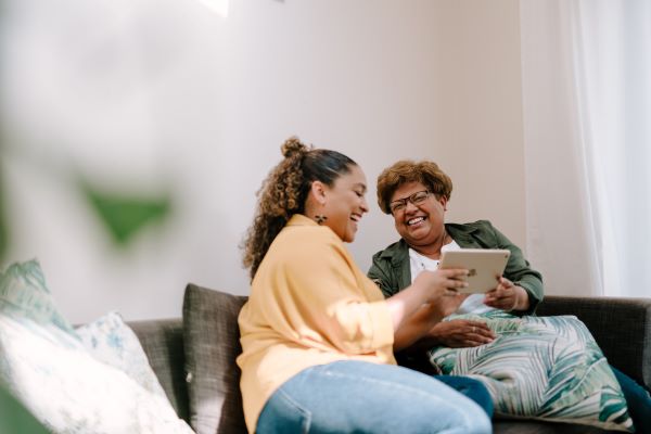 two women sat down laughing and holding a notepad