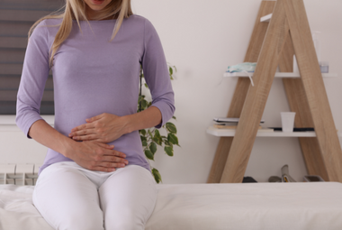 Pregnant women sitting down holding stomach