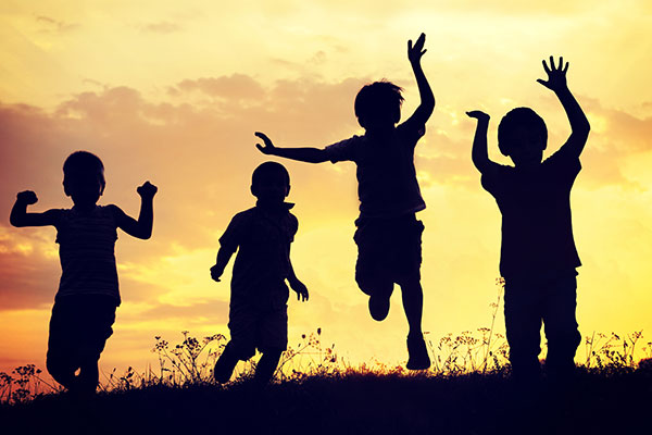 silhouette style picture that shows children running and jumping together