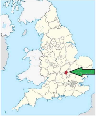 Map of England with local authority boundaries shown in light beige. The area of Milton Keynes in the East Midlands is highlighted in red, and a large green arrow points to the highlighted location from the east. Surrounding parts of Wales, Scotland, and the North Sea are visible in light blue and off-white.
