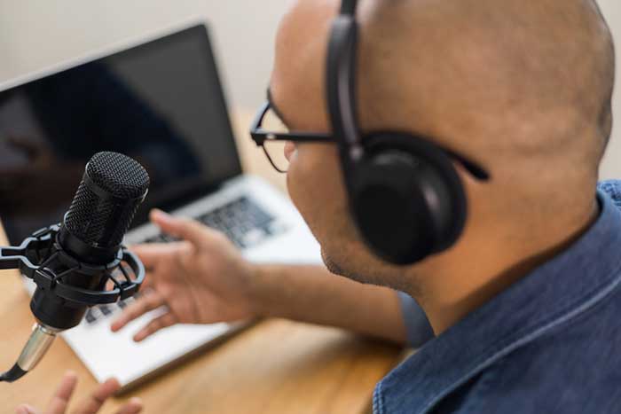 a close up of a man talking into a microphone for a podcast
