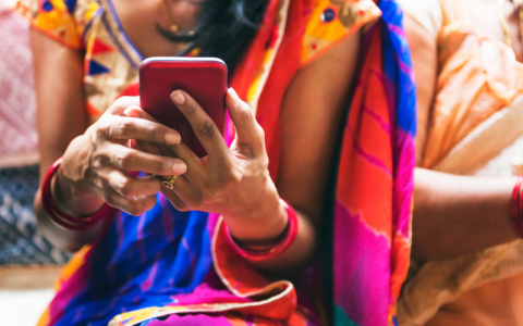 Lady in a brightly coloured sari looking at a mobile phone