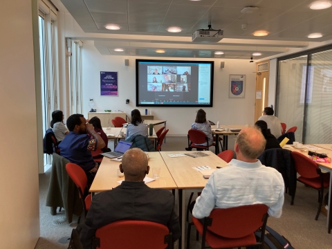 a photograph of the Poverty and Social Protection workshop showing attendees, both virtual and in person, listening to the speaker