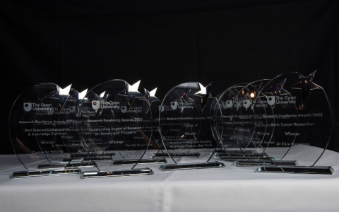 Research Excellence Award trophies sat on a table in front of a black background