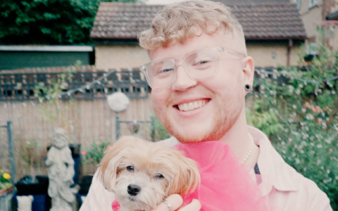 Solomon is pictured in a garden holding a small dog wearing a vibrant pink tutu