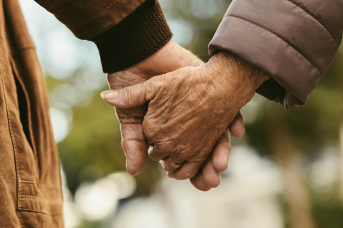 Elderly couple holding hands and walking outside