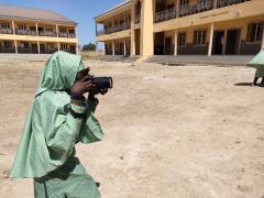 A young, African girl takes photos with a professional digital camera in Lake Chad region