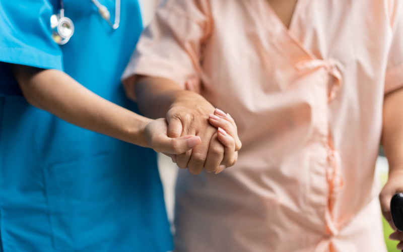 Hand of a caregiver supporting an elderly patient while walking