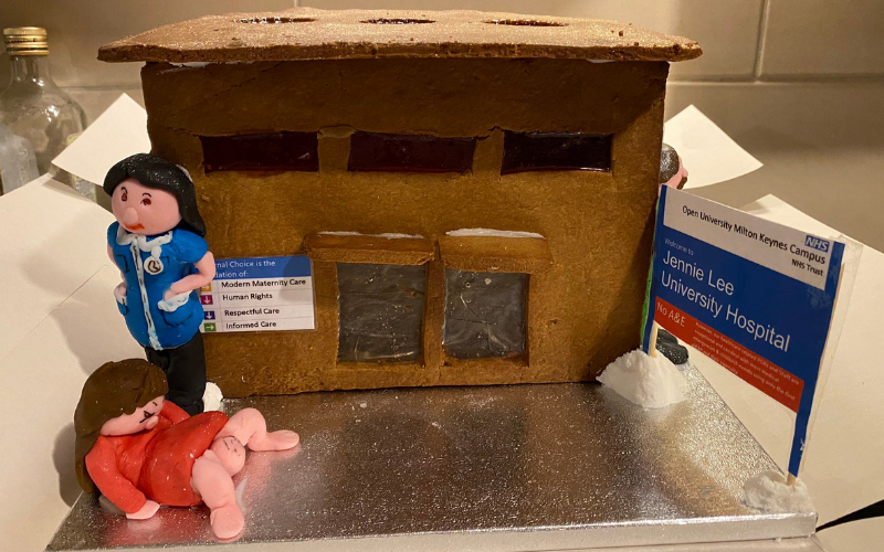  A detail from Anna Madeley's cake. It is a hospital made from gingerbread with an NHS sign outside reading, 'Welcome to Jennie Lee University Hospital". Made from fondant icing, a nurse stands over a mother giving birth outside the hospital.